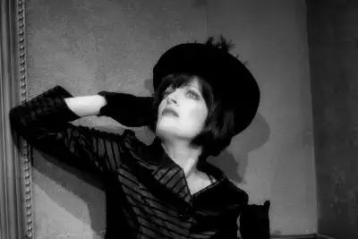 A woman with a black hat is looking up at the sky.