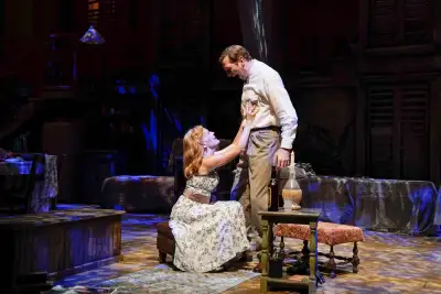 Men and women standing around a table with a lamp on it.