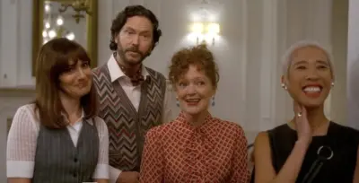 Woman stand together with a man wearing a striped vest.